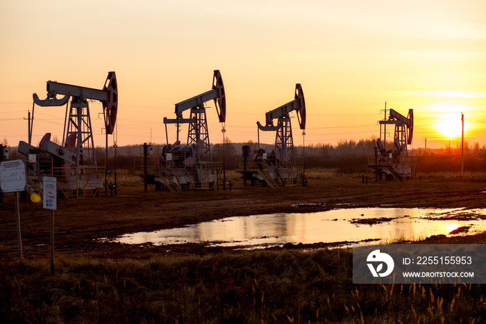 Working oil pump in rural place at sunset