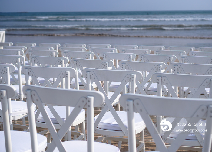 White chairs stand on the beach in rows. Outdoor conference. Religious meeting of the church for the wedding. Stock photo