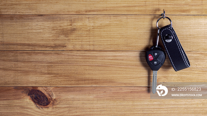 car key with remote control hanging at wooden wall.