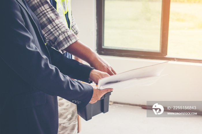 Architect and engineer discussion blueprint at construction site of new home