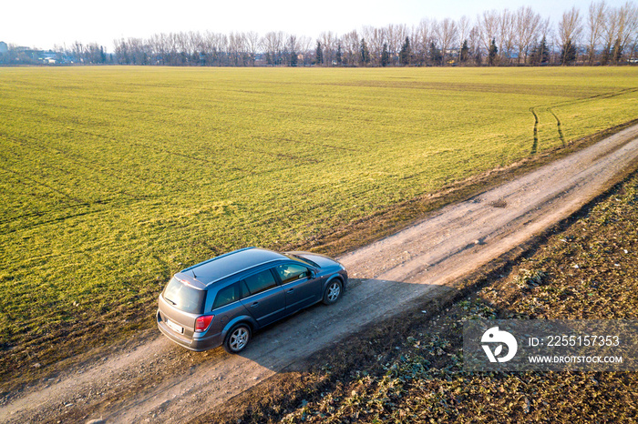 Aerial view of car driving by straight ground road through green