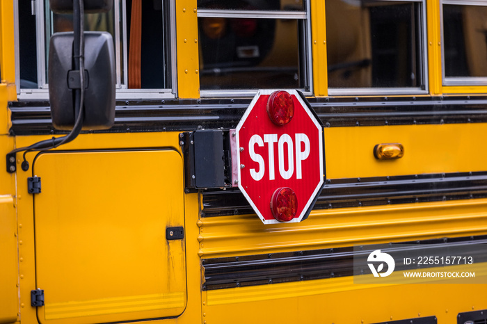 A close up of a yellow orange school bus with a red stop sign for back to school