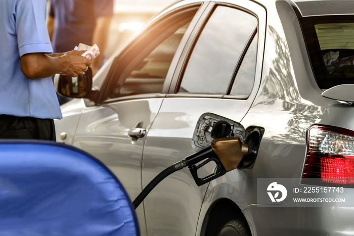 Car refueling on a petrol station and Employees filling, keep cash on hand.