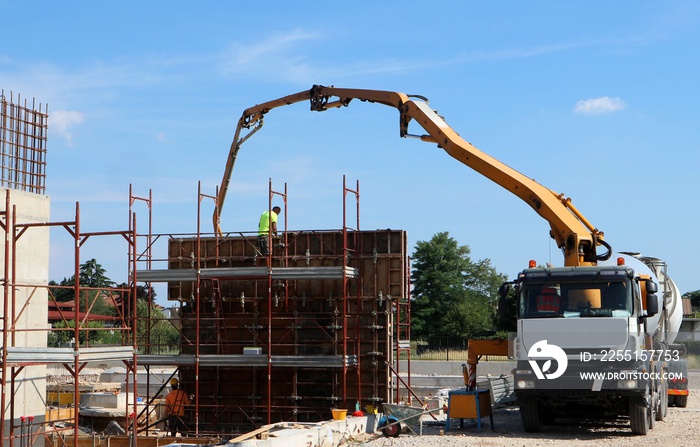 Cement mixer truck at work with its pump, during the build of the new palace first walls in the construction site