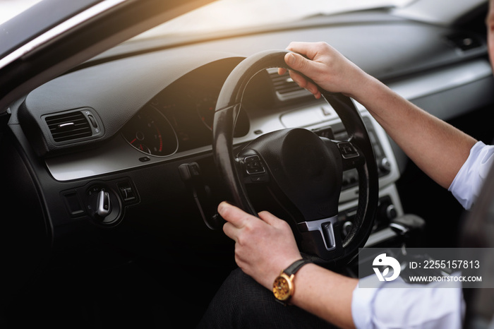 Cropped photo of arms businessman hands in classic white shirt and gold watch driving car hold wheel in new modern automobile vehicle black luxury rich salon Sale technology lifestyle concept.