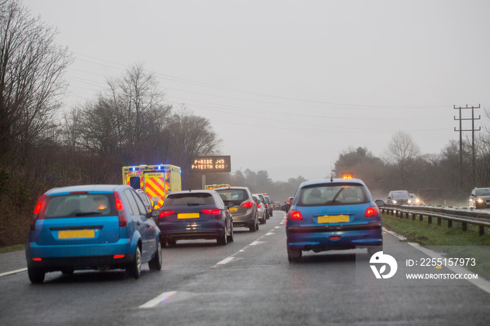 Ambulance parked on the hard shoulder of the M4 motorway, UK. Traffic is queuing and creating a hazard.