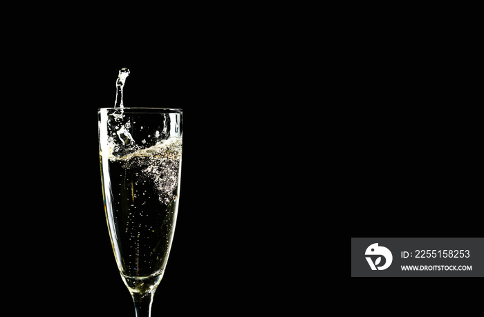 Glass of champagne with splash on dark background