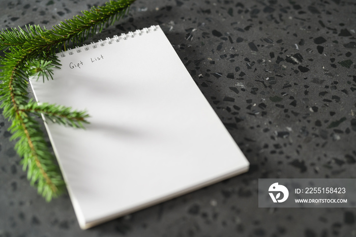 Notepad with gift list and spruce twig on terrazzo countertop