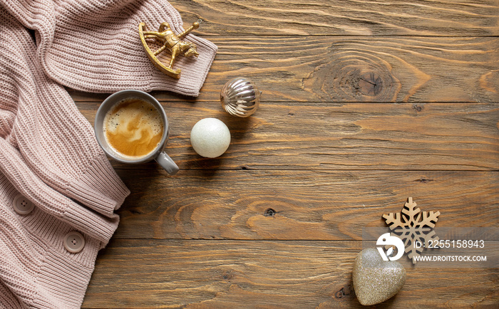 cozy christmas background. a gray-pink sweater, Christmas decorations and a cup of coffee on a brown wooden background. copy space. top view. flat lay style