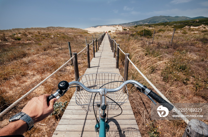 Riding a bike on the path to Guincho Beach in Portugal made on sand dunes