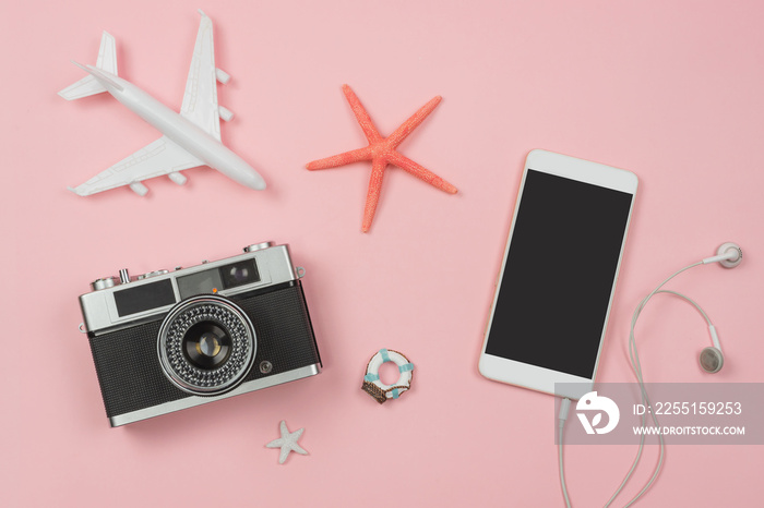 Retro camera with toy plane on pastel pink background and empty screen smart phone