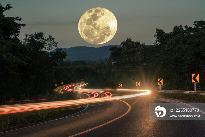 Car Light trail sparkly on Long macadamized S-curvy road with trees and beautiful full moon sky at night time: countryside Thailand