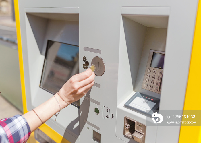 young woman paying at ticket machine in a public transport station