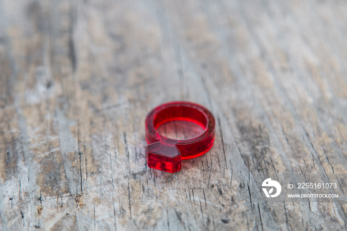 Modern red acrylic ring with diamond shape on distressed wooden table