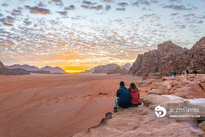 A young couple is watching at sunrise over wadi rum desert in Jordan