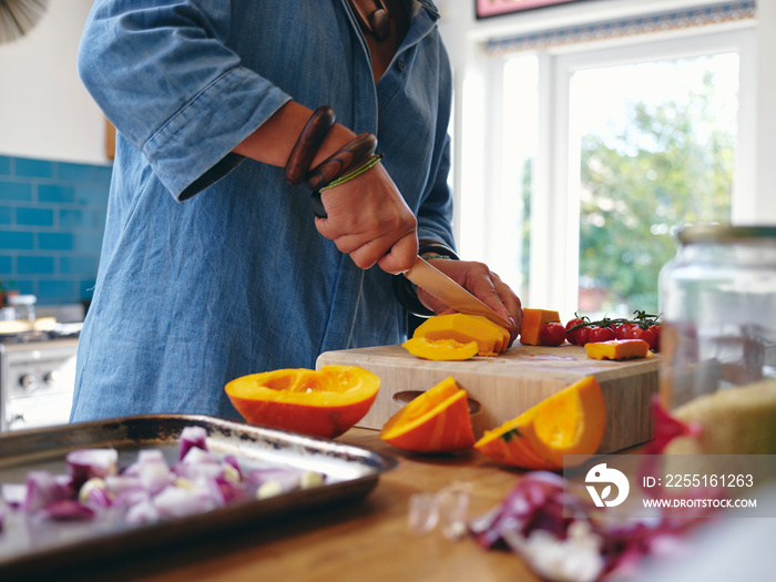 Woman chopping vegetables in kitchen, close up