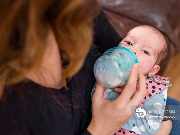 Mother bottle feeding infant daughter