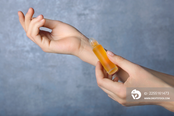 Female hands with bottle of perfume on light background