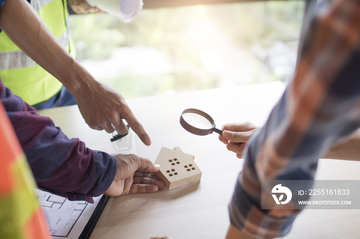 Inspection building concept, Inspector or engineer checking house construction by use magnifying glass on home model