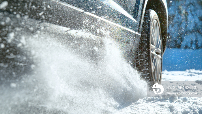 CLOSE UP, DOF: Fresh snow flies up from a large vehicle’s spinning wheel.