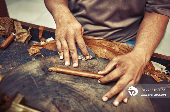 Closeup of hands making cigar from tobacco leaves. Traditional manufacture of cigars. Dominican Republic Vintage filter applied