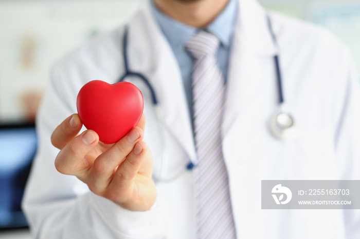 Man doctor hold red plastic heart and posing with stethoscope on neck