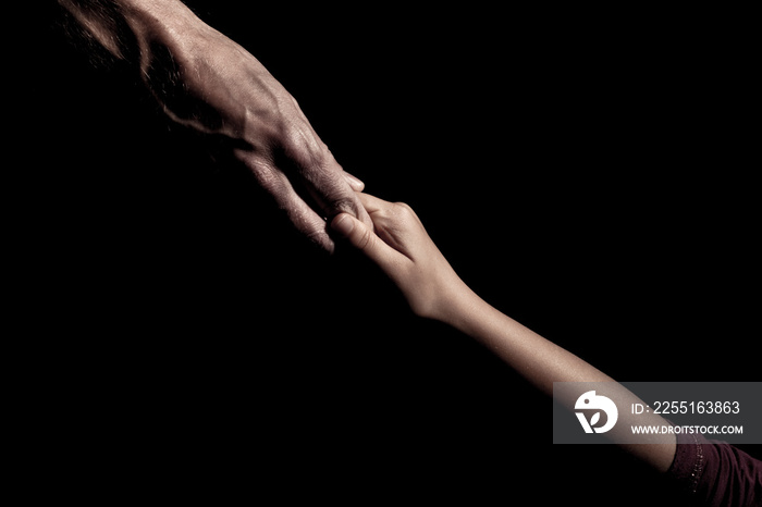 Old and young hands together on a black background holding hands