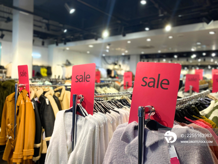 Sale signs above the clothes hangers in the mall. Black Friday in clothing stores.