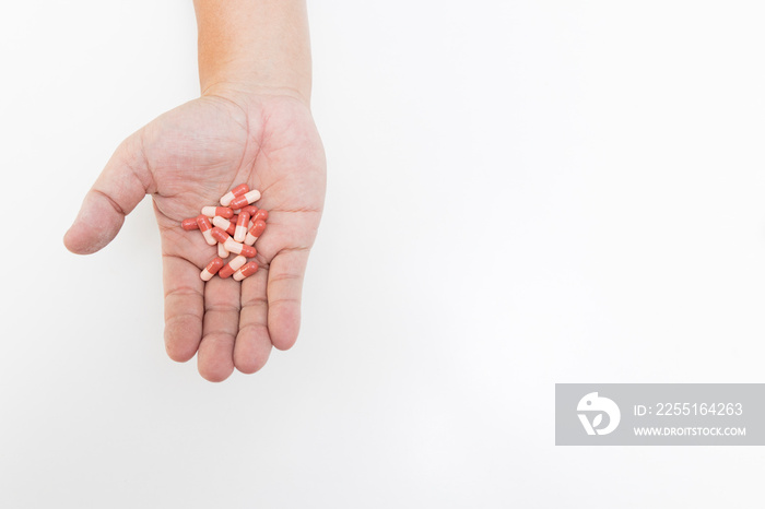 Top view of the pills on the hand and white background, A hand hold the capsules and drug with copy space.Woman taking vitamins and supplements.Medications against the COVID-19 and other conditions.