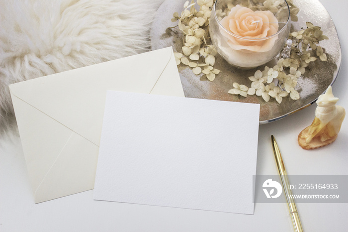 Elegant feminine stationery mockup scene with a blank paper greeting card, golden accessories, candle and flowers, on white background