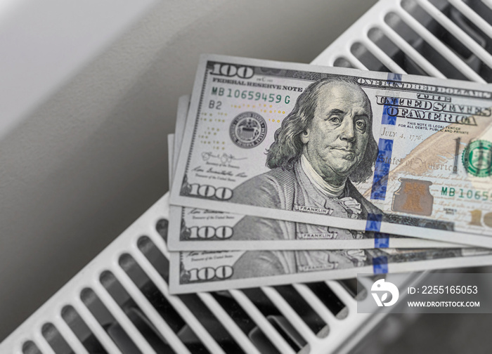 Banknotes of one hundred dollar bills on a heated radiator. High utility prices - concept.