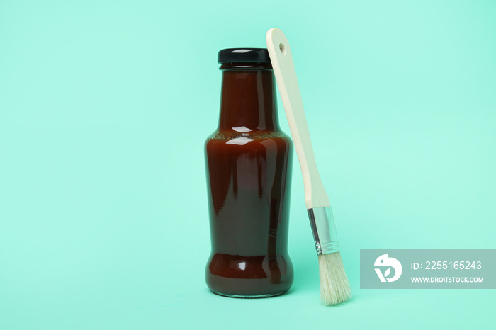 Bottle of barbecue sauce and brush on mint background