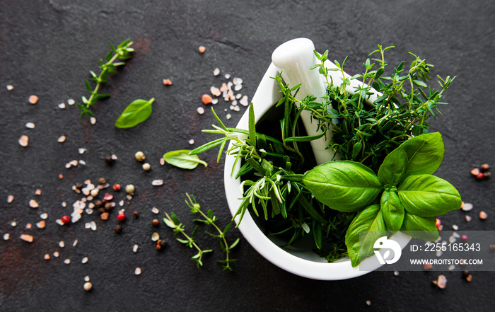 Bunch of aromatic herbs in mortar on a black concrete background