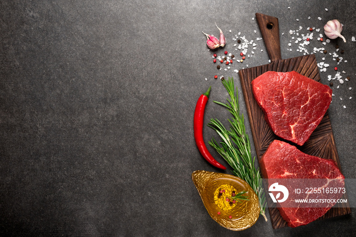 Raw beef marbled steak on cutting board with rosemary and spices. Top view and copy space