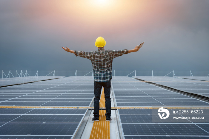 Technician inspecting the installation of solar panels standing with arms outstretched on solar panels against sun sky background, solar power clean energy, concept great power