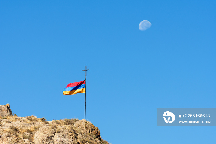 Armenian flag against a blue sky with a visible moon