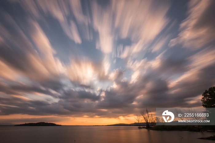 Beautiful wide angle, long exposure view of a lake at sunset, with an huge sky with moving clouds