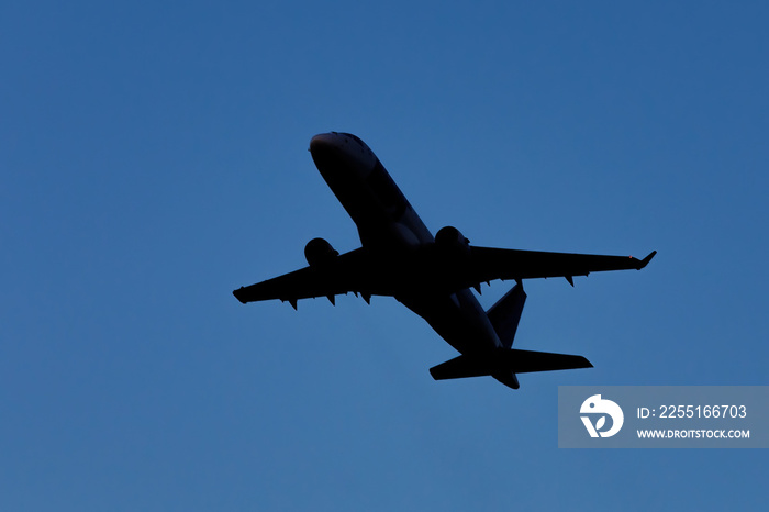 A large modern plane flies in the sky, a view from below from the ground to the belly of the aircraft.