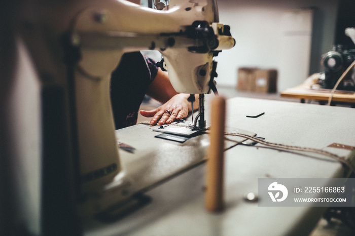 Manos trabajando en fábrica. Trabajador cosiendo trenzas de yute para calzado.