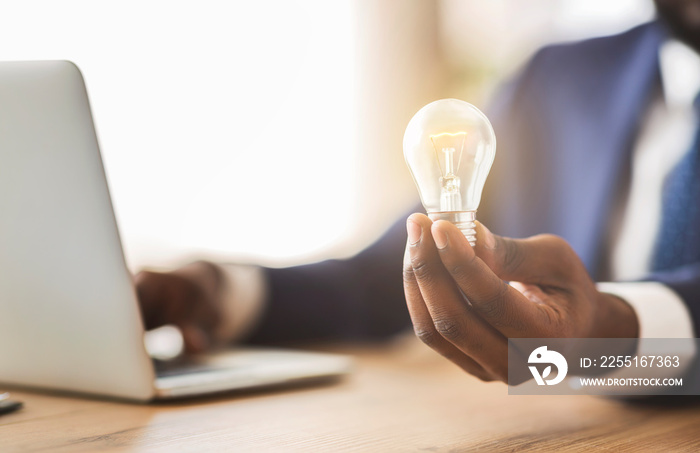 Businessman holding illuminated light bulb, sitting in office