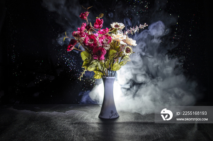 Picturesque purple spring flowers in glass vase standing in a row on a dark background with stars with light and fog. Close up