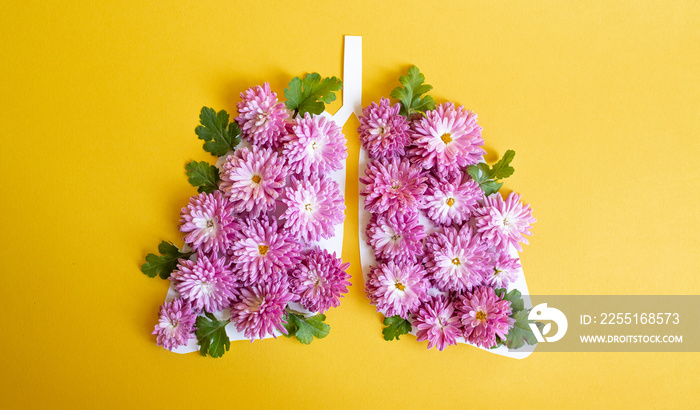 creative image in the shape of paper lungs decorated with pink flowers on a yellow background. copy space. top view. flat lay. concept of world tuberculosis day, world no tobacco day