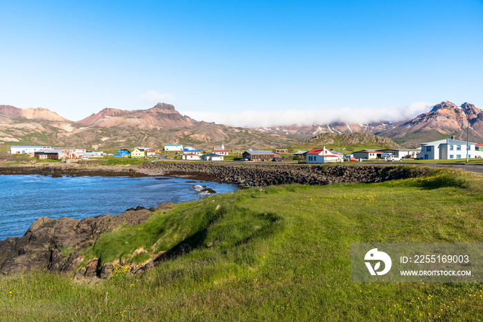 Small coast village at the foot of towering mountains in Iceland on a clear summer day