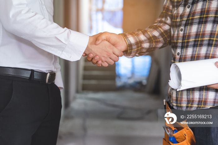 construction worker and contractor. Client shaking hands with team builder in renovation site.