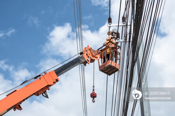 Two electrician workers are climbing on the electric poles to install and repair power lines.