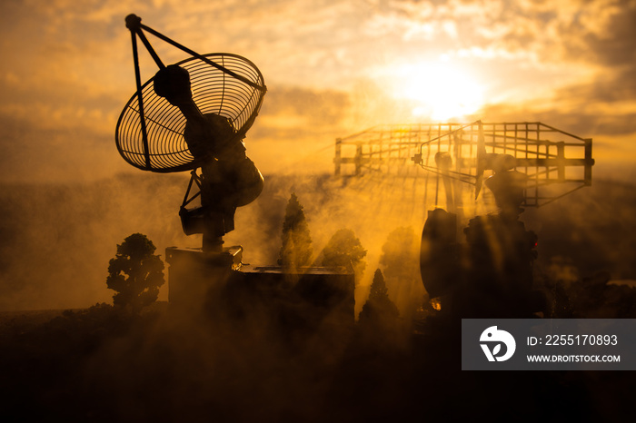 Silhouettes of satellite dishes or radio antennas against sunset sky. Space observatory.