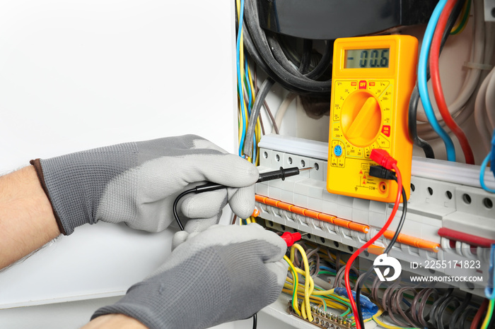 Young electrician measuring voltage in distribution board, closeup