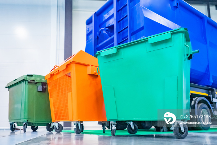 Garbage containers on wheels. Multi-colored containers next to a garbage machine. Separate waste containers. Garbage collection for subsequent disposal. Concept - care for the environment.