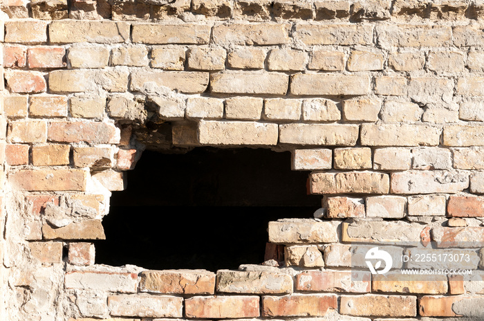 Damaged brick wall of house or building with hole destroyed by grenade in the war zone