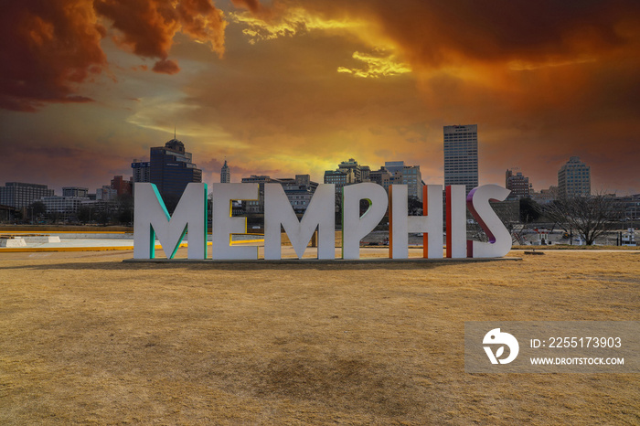 a gorgeous shot of the colorful Memphis sign with gorgeous red sky and powerful clouds at sunset with yellow winter grass at Mud Island Park in Memphis Tennessee USA